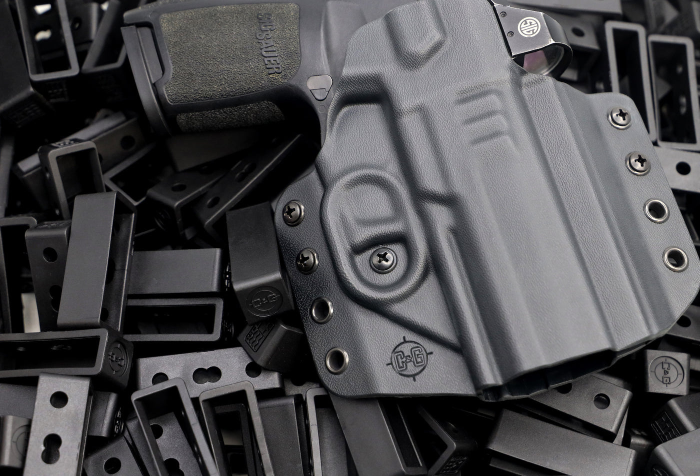 Decorative image of C&G OWB Kydex Holster holstering a Sig Sauer on top of many C&G OWB Belt loops. 